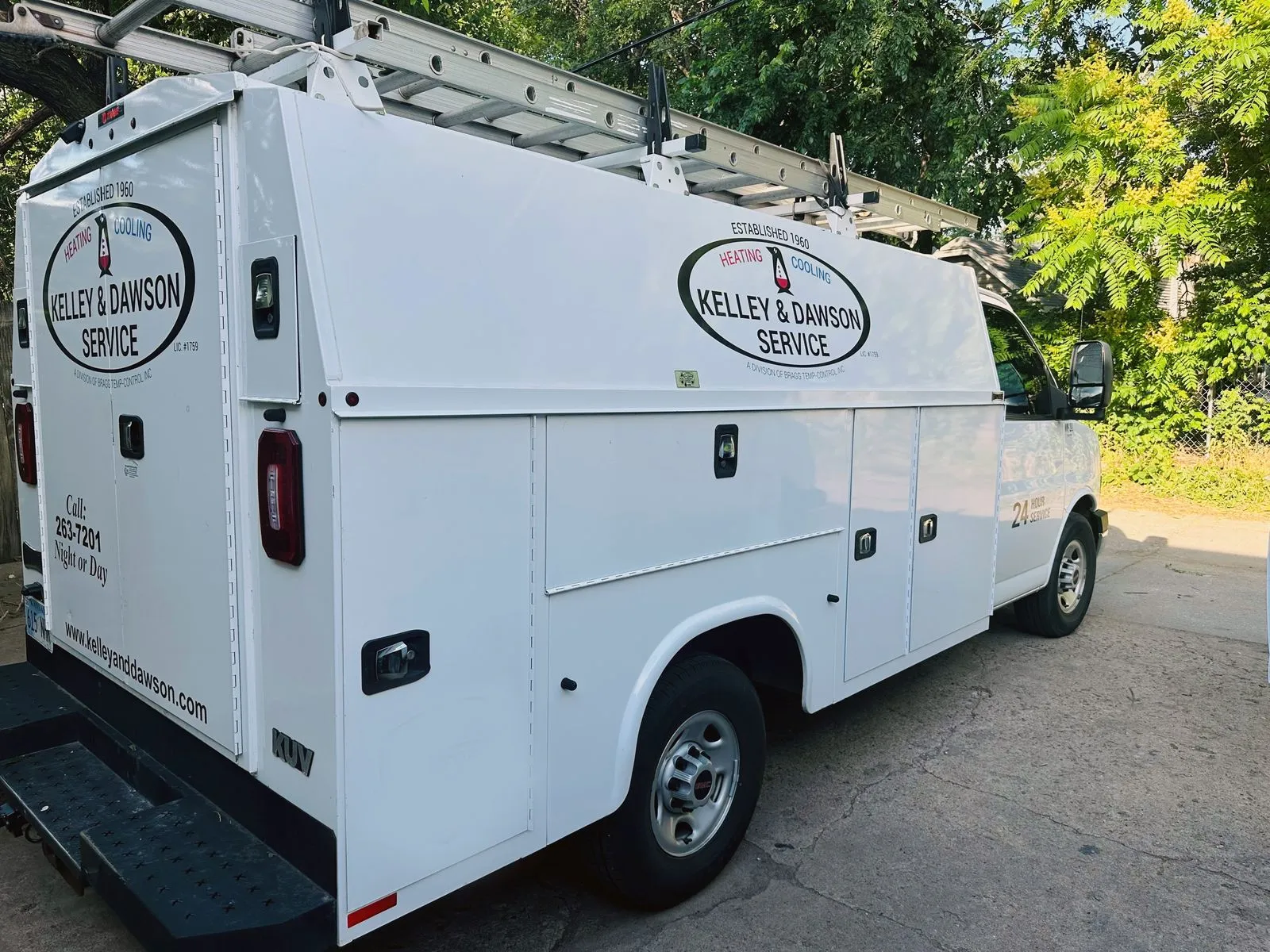 Rear view of a Kelley & Dawson Service 24-hour utility truck with roof ladder rack