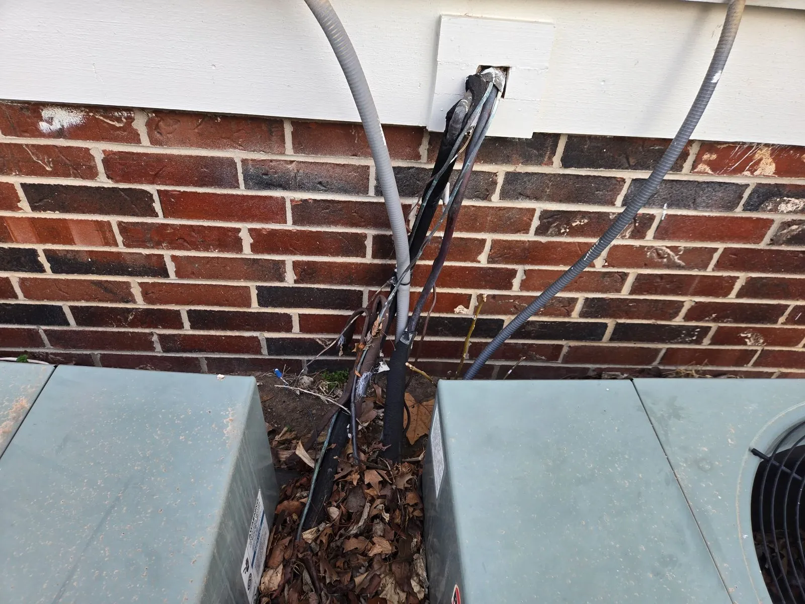 Refrigerant line set and wiring running between two AC condensers at a brick home