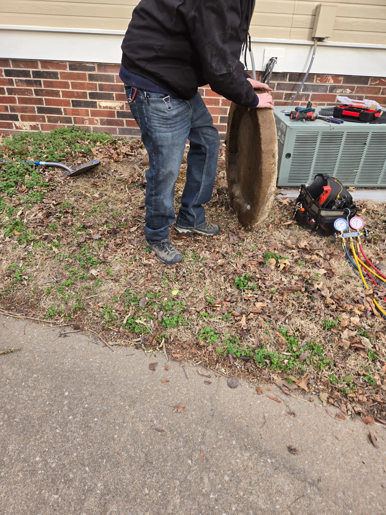 Technician placing a composite equipment pad for an outdoor AC condenser