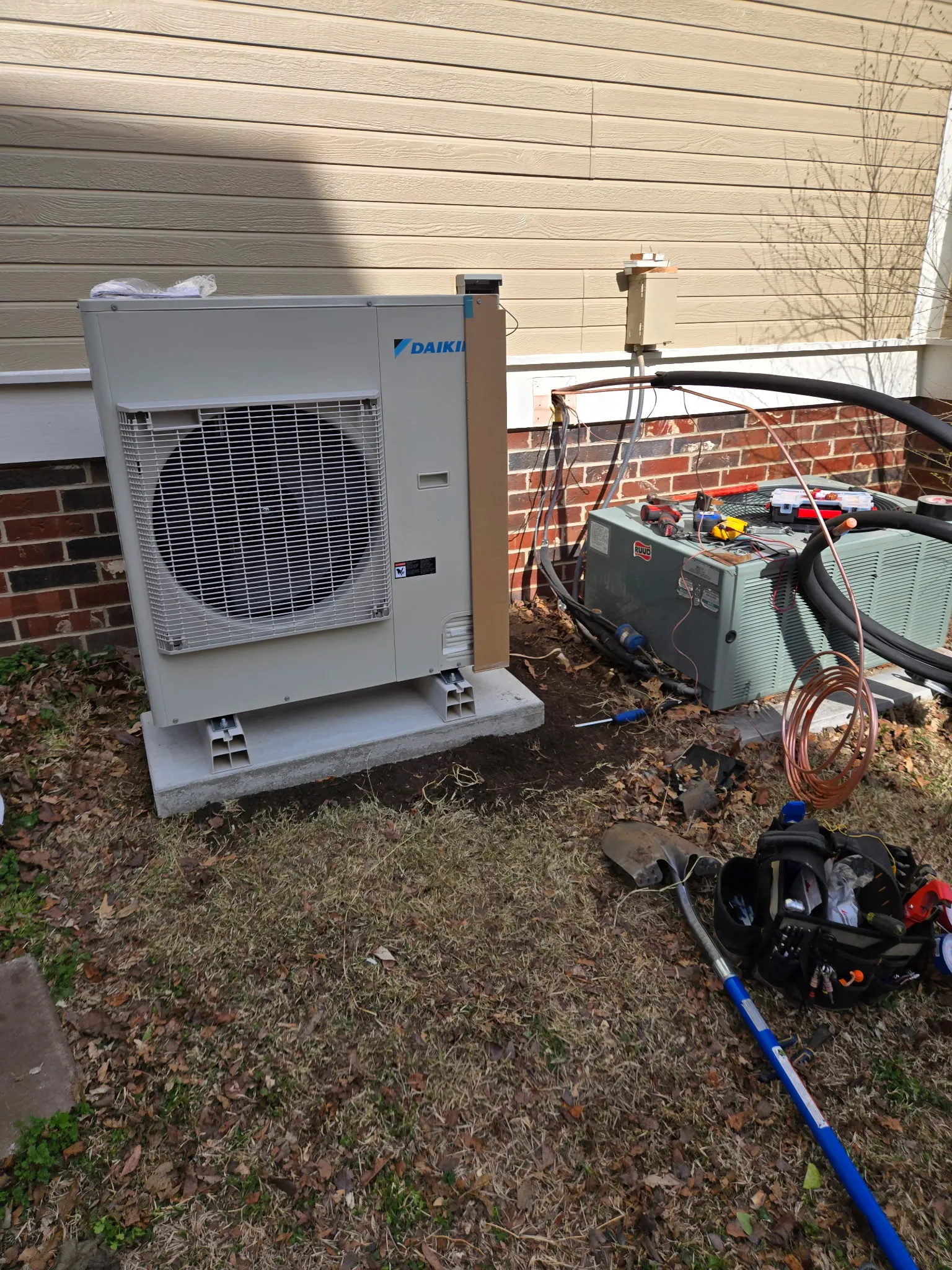 Heat pump condenser set on its pad during an outdoor installation