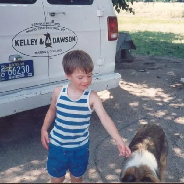 Throwback photo of a young family member and dog beside an early Kelley & Dawson van