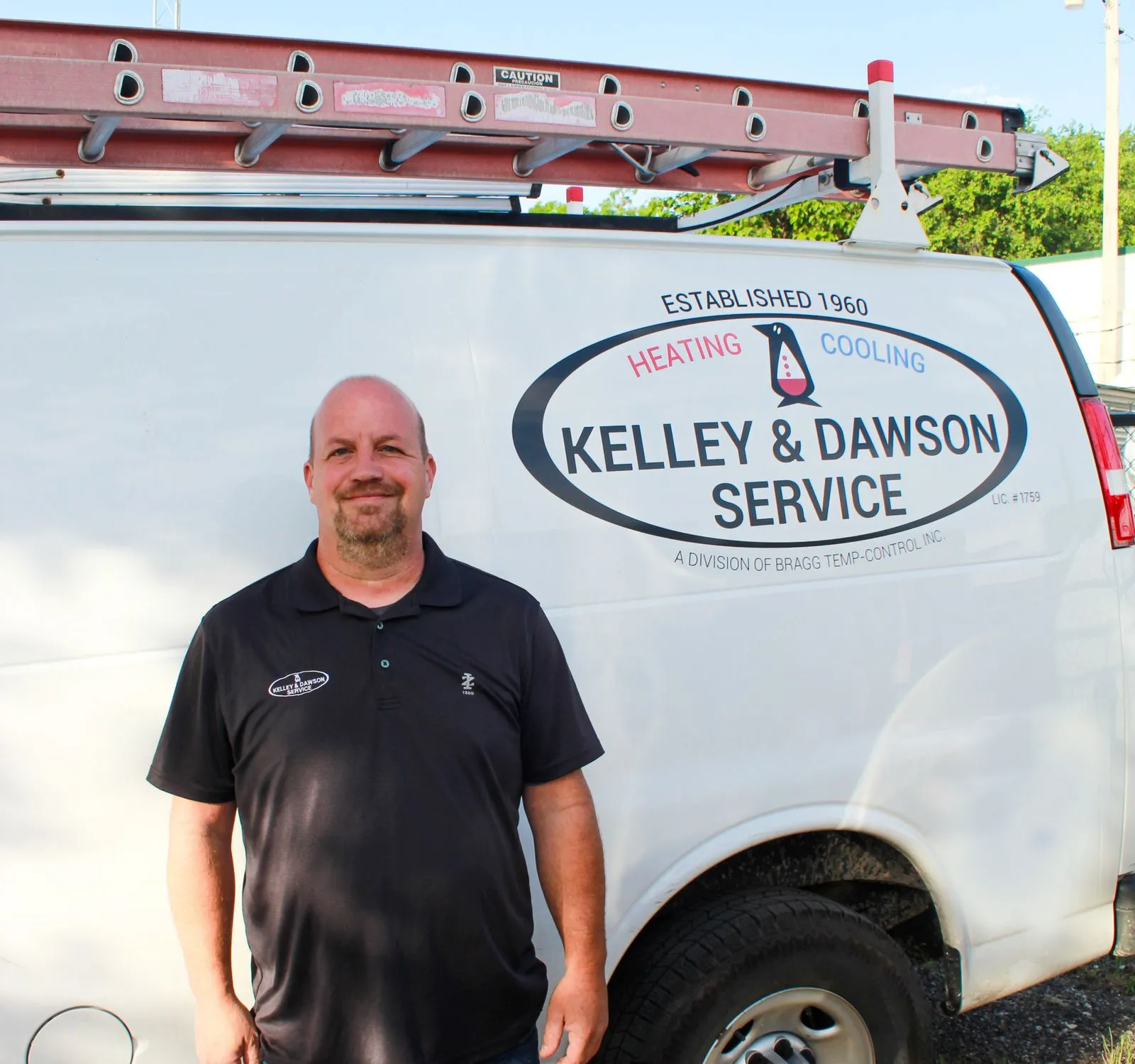Kelley & Dawson team member in front of a service van marked Established 1960